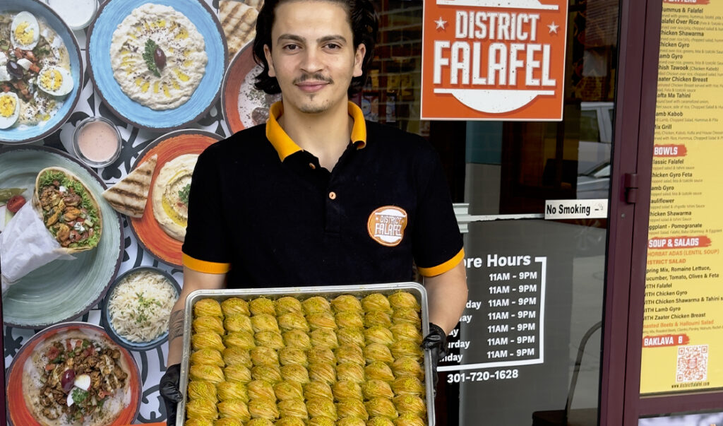 Man hold a tray of desserts outside of District Falafel