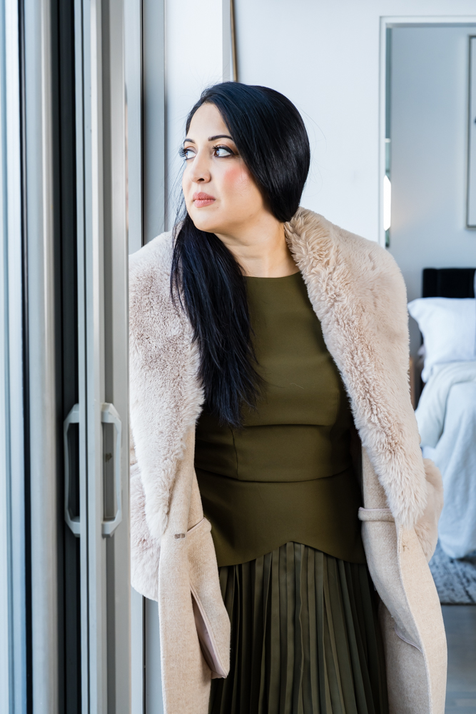 Luxury Real Estate agent looking in deep though out the window elegantly dressed about how she is winning within the real estate industry