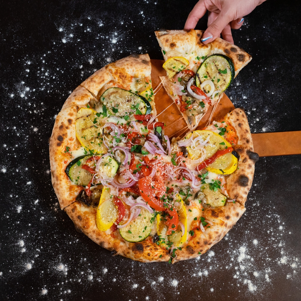 neapolitan pizza with hand pulling a slice